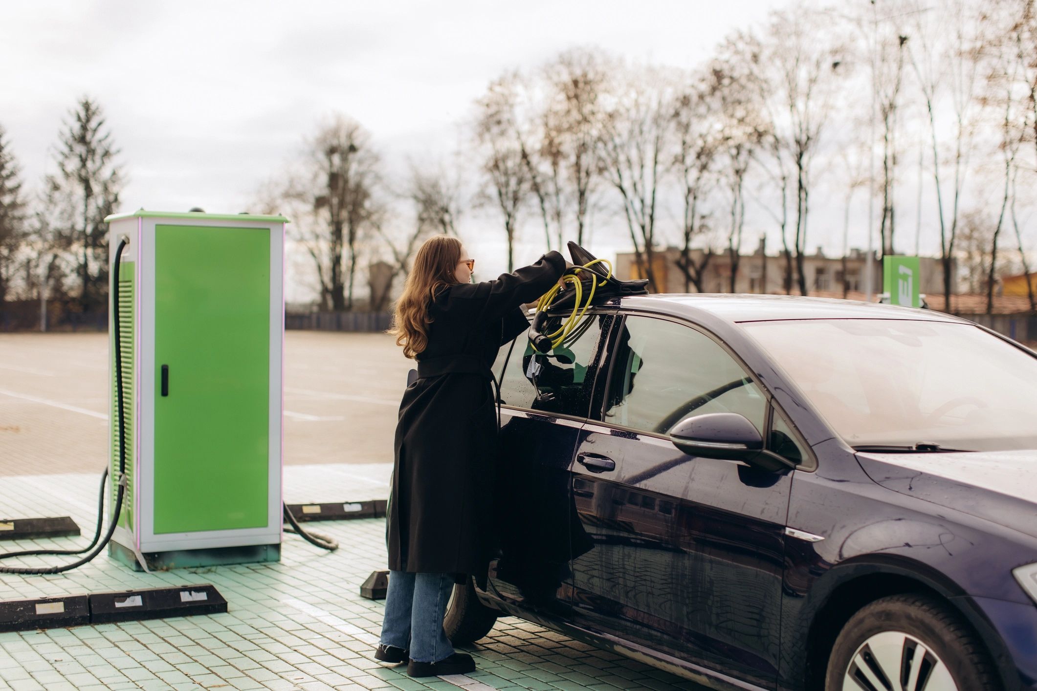 Woman charging an electric vehicle at a public station